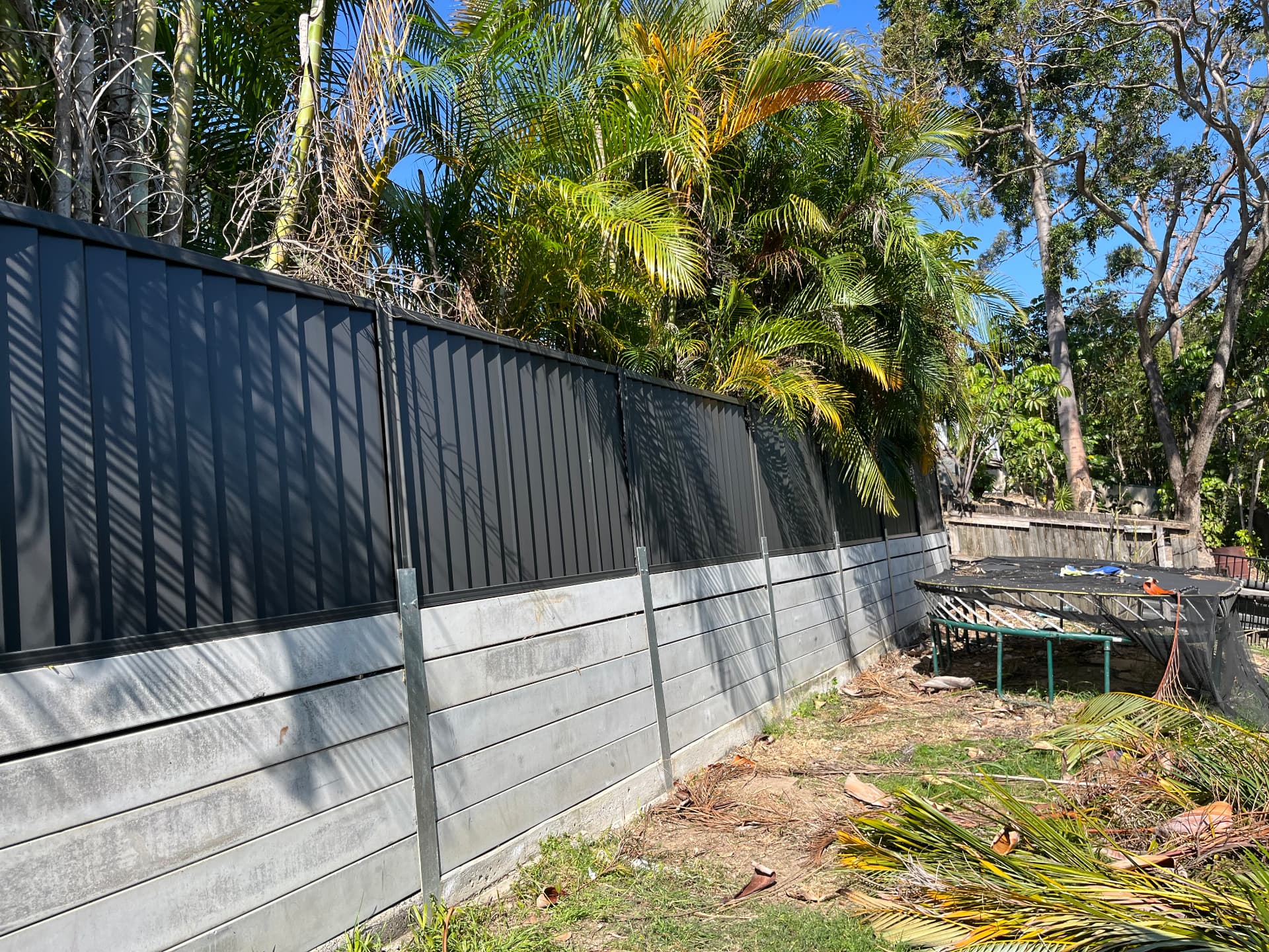 Dark colourbond fence with retaining wall on a sloping block